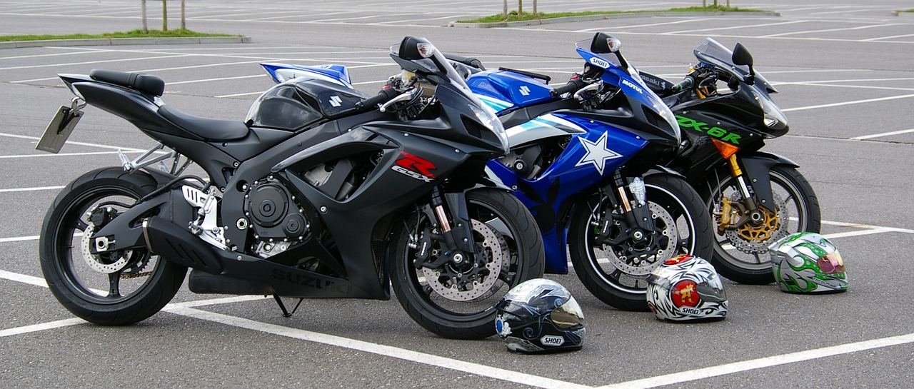 An image of three parked motorcycles next to three helmets.