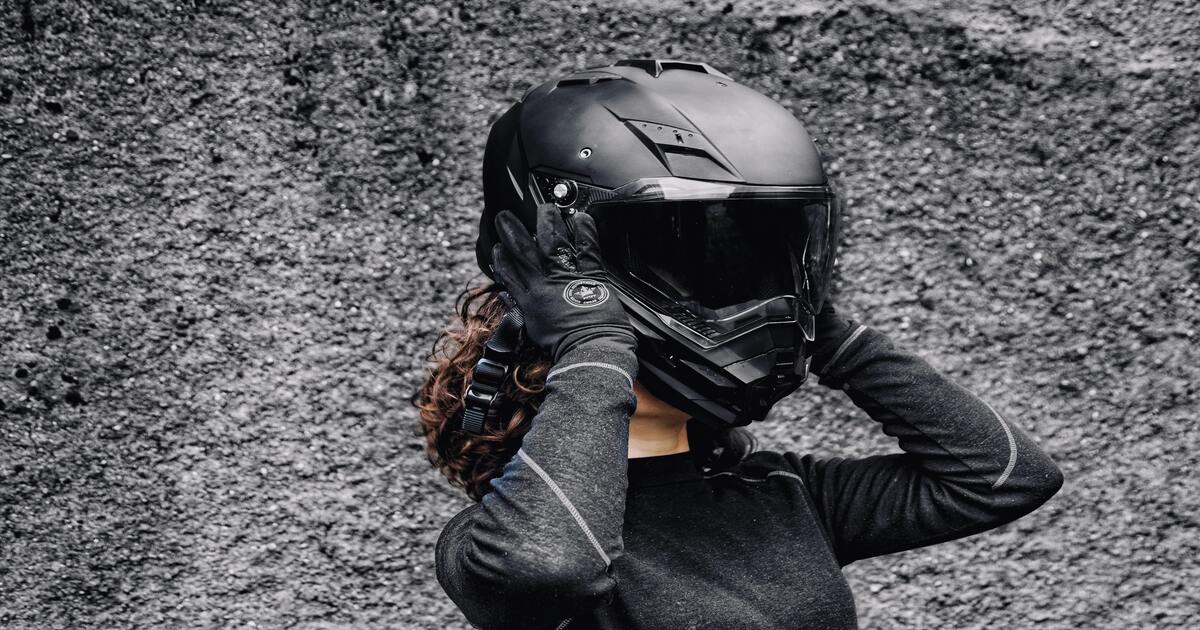 A woman putting on a black modular helmet.
